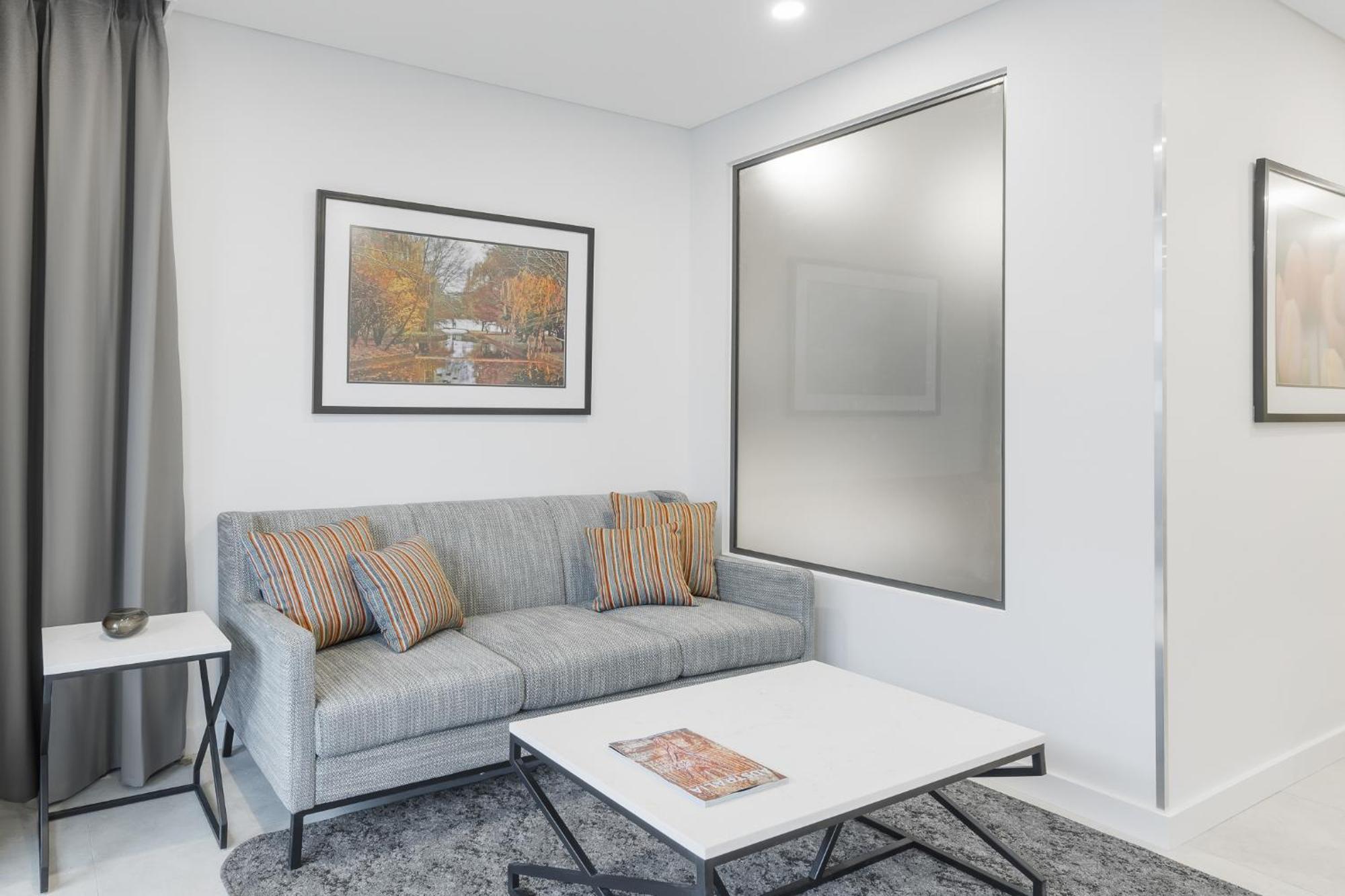 Meriton Suites Camberra Exterior foto A living room with a sofa
